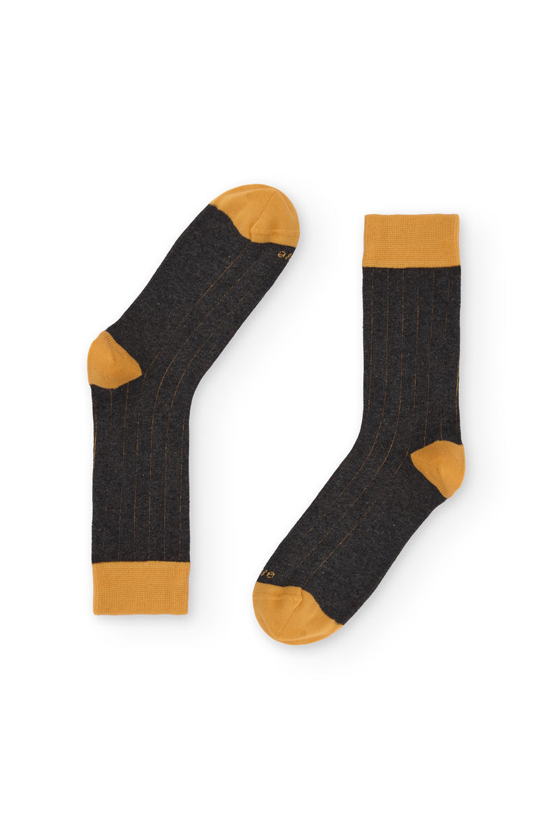 Calcetines gris oscuro de canalé, caña alta, 90 % algodón y logo NAIVE en la puntera; tejidos en España.