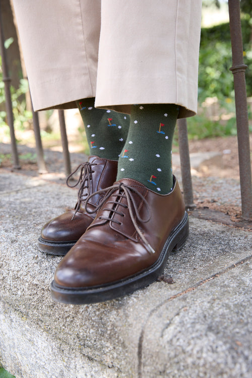 Calcetines de fondo verde con motivo de golf, caña alta, 90 % algodón, logo bordado en la punta; hechos en España.