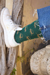 Calcetines de fondo verde con motivo de monos, caña media, 90 % algodón, logo bordado en la punta; hechos en España.