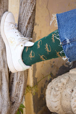 Calcetines de fondo verde con motivo de monos, caña media, 90 % algodón, logo bordado en la punta; hechos en España.