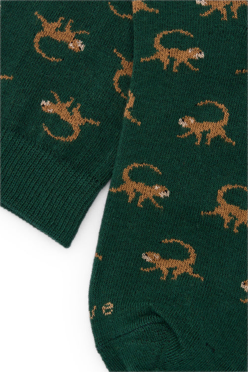 Calcetines de fondo verde con motivo de monos, caña alta, 90 % algodón y logo bordado en la punta; hechos en España.