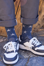 Calcetines premium azul oscuro con estrellas grises, caña media, 90 % algodón y logo en la puntera; hechos artesanalmente en España.