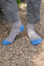 Calcetines lisos grises de canalé, caña media, 90 % algodón y logo bordado; hechos artesanalmente en España.