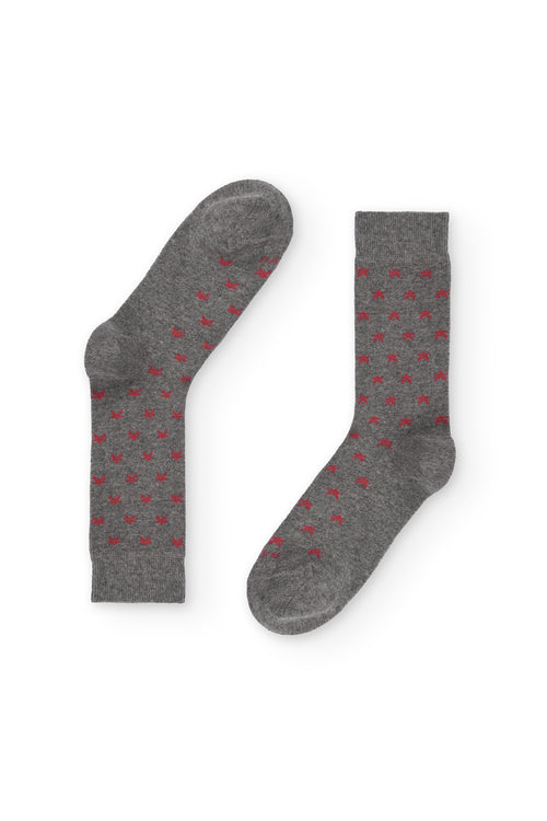 Calcetines gris medio de caña alta con estrellitas rojas, 90 % algodón y logo NAIVE en la puntera; tejidos en España.