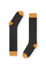 Calcetines de canalé gris oscuro, caña alta, 90 % algodón y logo NAIVE en la puntera; tejidos en España.