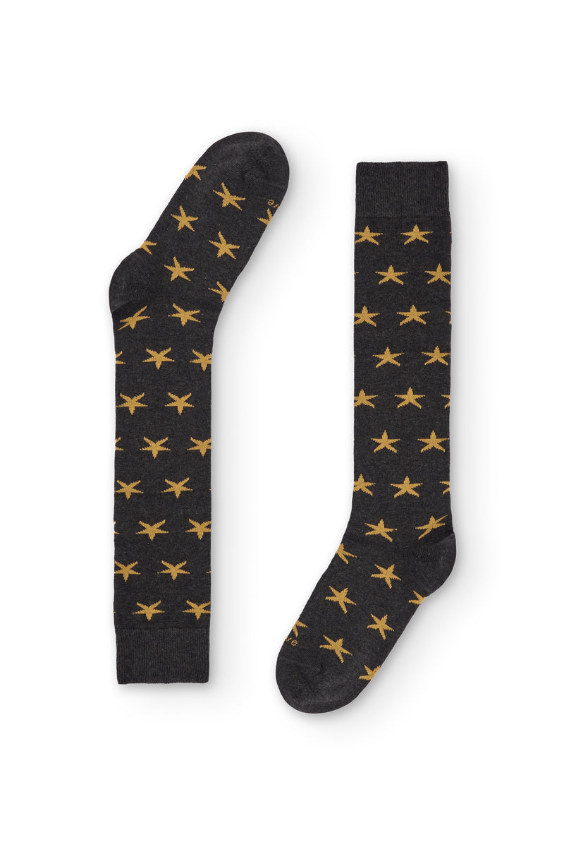 Calcetines gris oscuro de caña alta con estrellas amarillas, 90 % algodón y logo NAIVE en la puntera; tejidos en España.