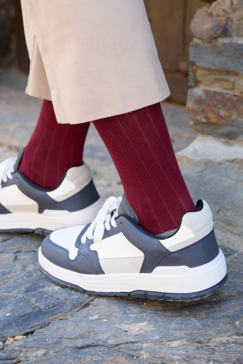 Calcetines lisos burdeos, canalé clásico, caña media y logo bordado; 90 % algodón, hechos artesanalmente en España.