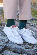 Calcetines premium verde bosque con puntitos rosa pastel, caña media, 90 % algodón y detalle de logo; hechos artesanalmente en España.