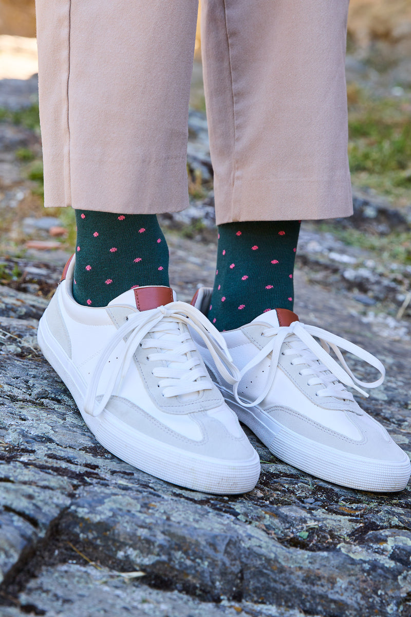 Calcetines premium verde bosque con puntitos rosa pastel, caña media, 90 % algodón y detalle de logo; hechos artesanalmente en España.