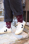 Calcetines burdeos con huellas, tejido transpirable de algodón, poliamida y lycra, caña media y marca NAIVE en la puntera.