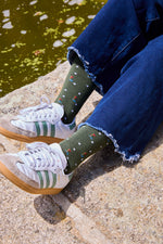Calcetines mid-calf verde con diseño de palos y pelotas de golf, mezcla de algodón y lycra, detalle de logo, fabricación española.